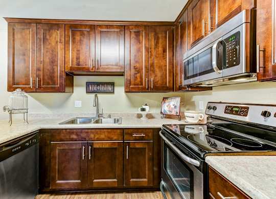 A kitchen with dark wood cabinets and black appliances.