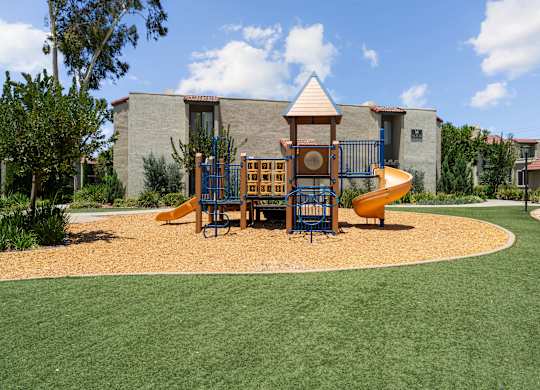 A playground with a yellow slide and a brown and blue play structure.