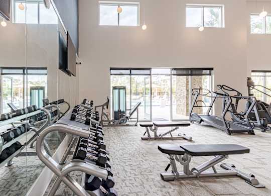 A gym with a variety of equipment including treadmills, weights, and exercise machines.