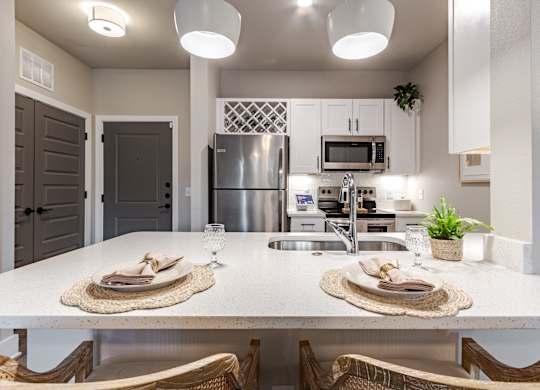A modern kitchen with a dining table set for two.