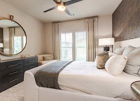 A bedroom with a large bed, a dresser, and a ceiling fan.