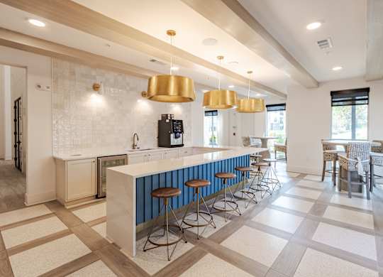 A kitchen with a white counter and blue bar stools.