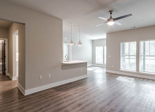 A spacious living room with a ceiling fan and hardwood floors.