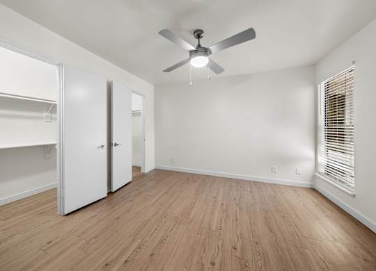 A room with a ceiling fan and wooden flooring.