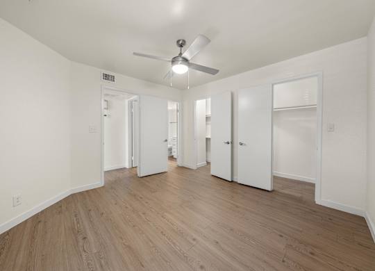 A room with a ceiling fan and wooden flooring.
