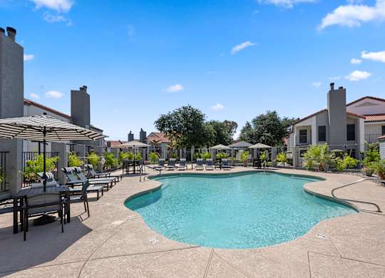 A large outdoor swimming pool surrounded by lounge chairs and umbrellas.
