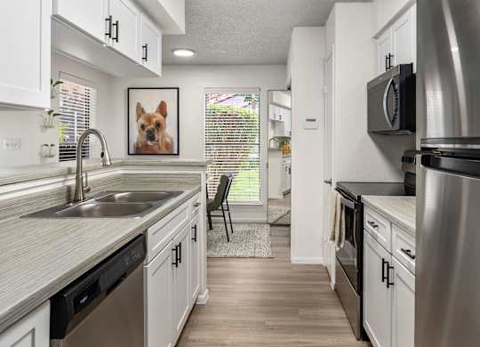 A kitchen with a stainless steel refrigerator and black appliances.