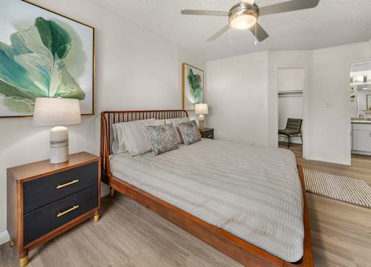 A bedroom with a bed, nightstand, and a painting on the wall.