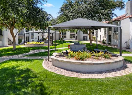 A sunny day at a park with a pavilion and a fire pit.