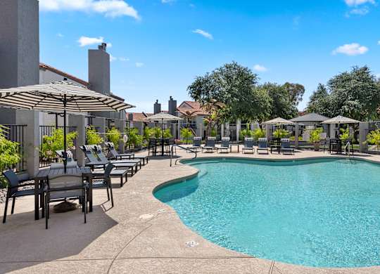 A large outdoor swimming pool surrounded by lounge chairs and umbrellas.