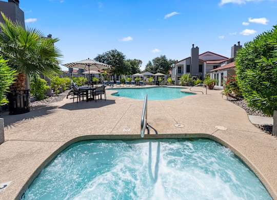 A hot tub in the middle of a pool surrounded by a house and trees.