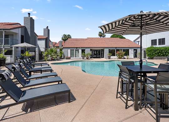A poolside area with lounge chairs and a table.
