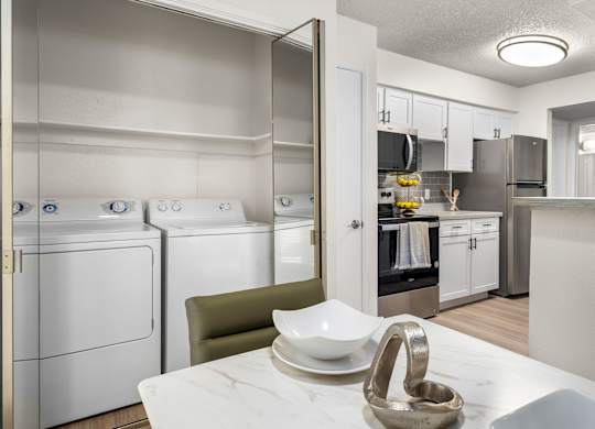 A modern kitchen with white appliances and a marble table.