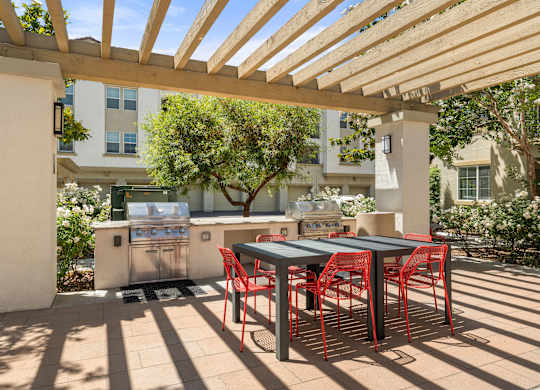 A patio with a table and chairs under a wooden pergola.