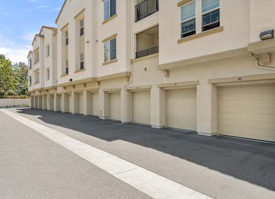 A row of beige townhouses with garages on the side.