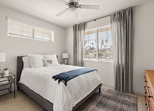 A bedroom with a large bed and a ceiling fan.