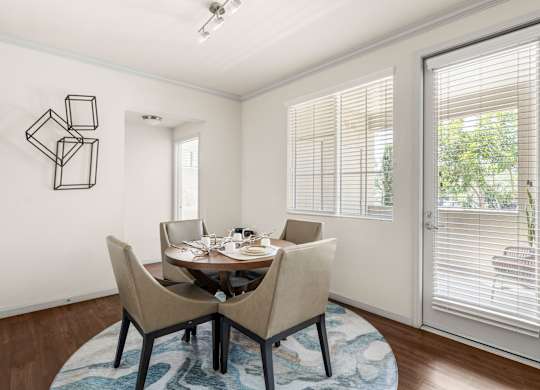 A dining room with a table set for two and a wall art.