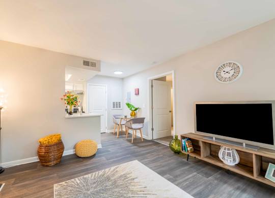A living room with a television, a chair, a table, and a clock on the wall.