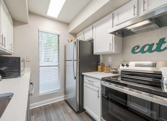 A kitchen with a refrigerator, oven, and microwave.
