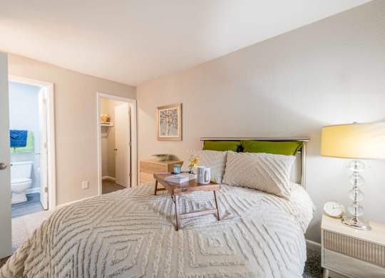 A bedroom with a large bed and a nightstand with a lamp.