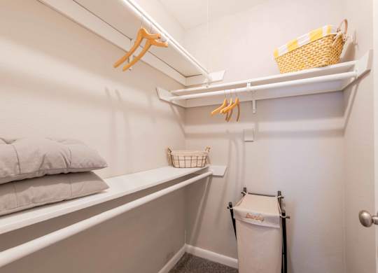 A small white closet with a basket on top shelf.