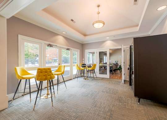 a room with high top tables with yellow chairs