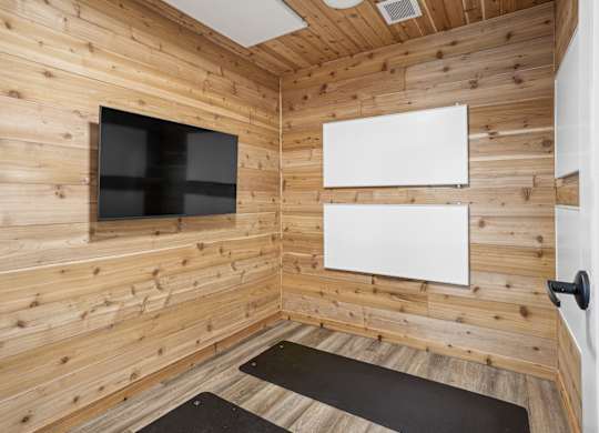 A room with wooden walls and a black mat on the floor.