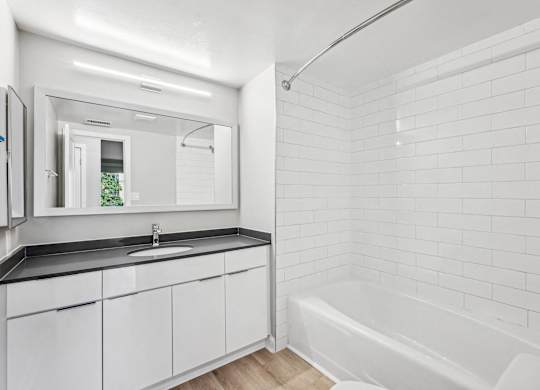 a white bathroom with a tub and a sink and a mirror