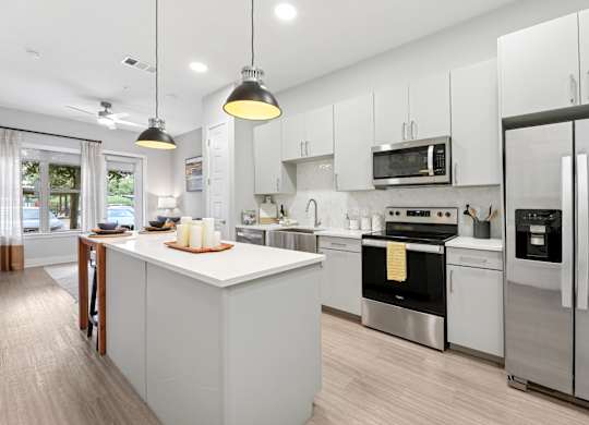 A modern kitchen with a white island and stainless steel appliances. at Trailhead, Austin, Texas