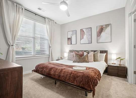 A bedroom with a bed, nightstands, and pictures on the wall.