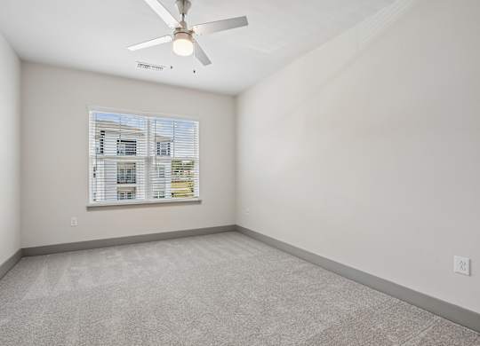 A room with a ceiling fan and a window with blinds.