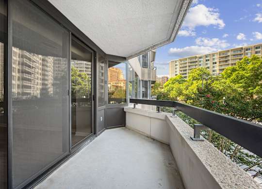 a long balcony with glass doors and a city in the background