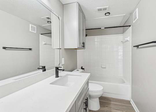 A white bathroom with a toilet, sink, and bathtub at Clear Creek Meadows Apartments, Texas