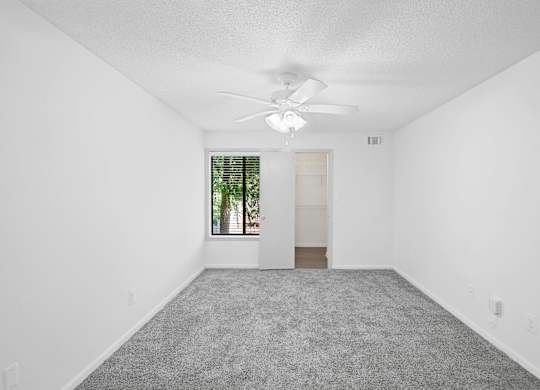 A room with a ceiling fan and carpeted floor.