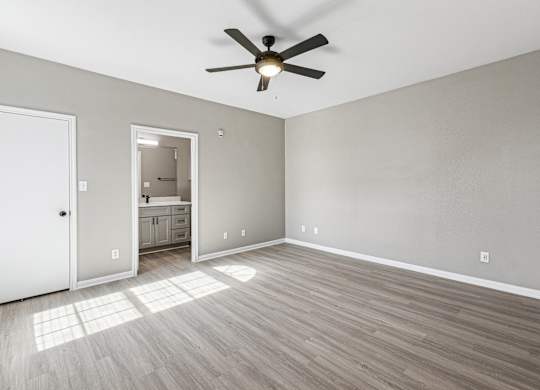 A room with a ceiling fan and light, hardwood floors, and a white door at Clear Creek Meadows Apartments, Copperas Cove, TX, 76522
