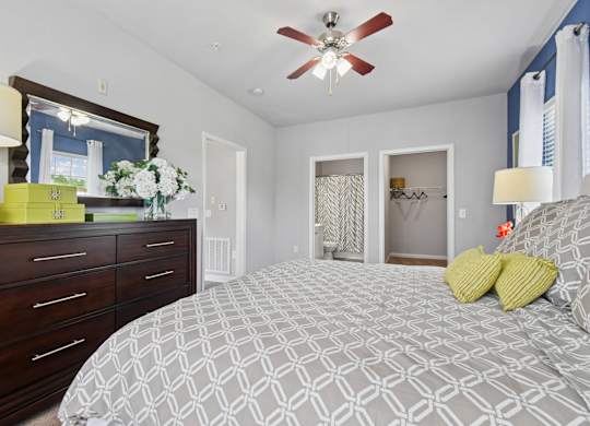 A bedroom with a patterned bedspread and a ceiling fan.