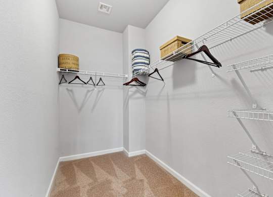 A walk in closet with clothes hanging on racks and shelves.