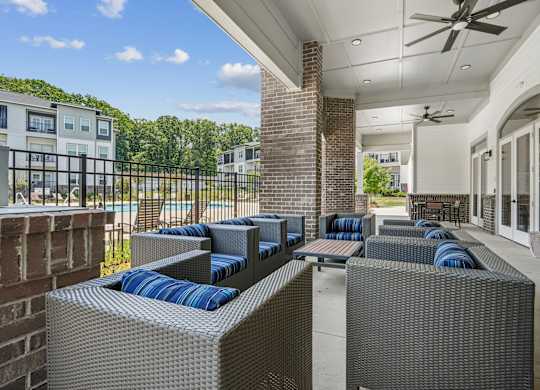A patio with grey wicker furniture and a brick pillar.