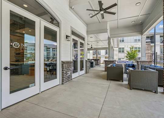 A patio area with a table and chairs and a ceiling fan.