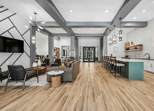 A modern living room with a wooden floor and a kitchen area in the background.