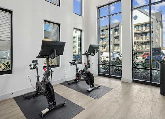 A gym room with exercise bikes and a television.