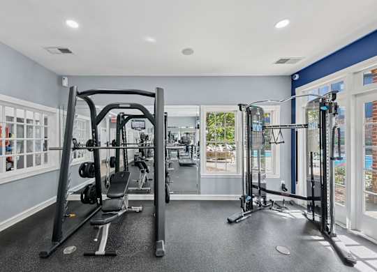 A gym with a variety of equipment including a squat rack, a leg press machine, and a bench press.