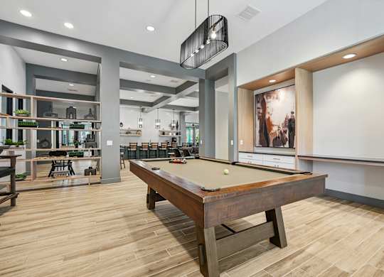 A pool table is in the middle of a room with a bar and a dining area.