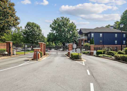 A blue building is behind a gate and a brick wall.