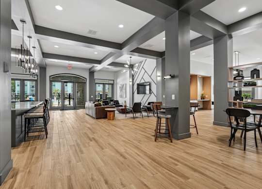 A modern open plan kitchen, dining and living room with wood flooring and dark grey columns.