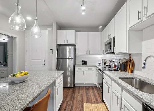A modern kitchen with white cabinets and a granite countertop.