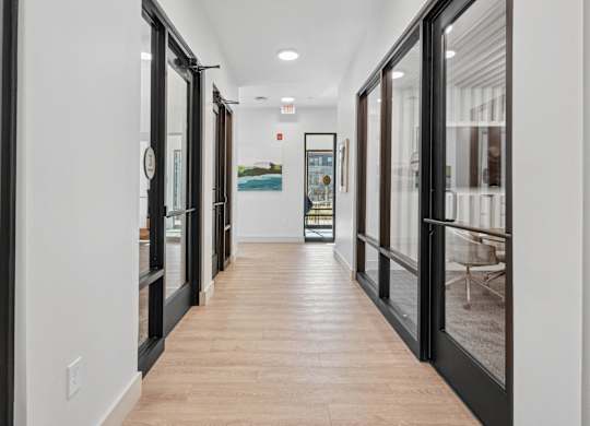 A long hallway with black doors and wood floors.