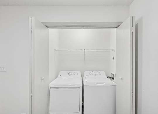 Two white front loading washing machines in a small laundry room.