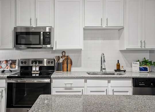 A modern kitchen with white cabinets and a granite countertop.