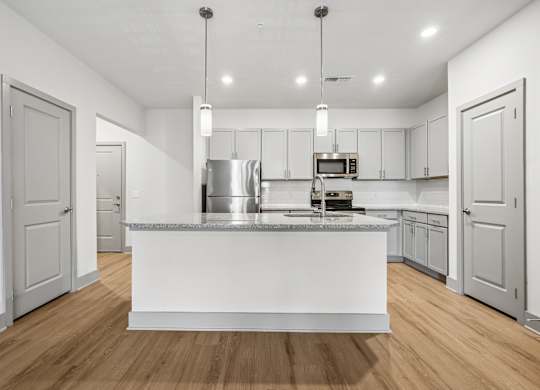 A modern kitchen with a white island and wooden floors.